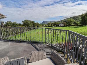 a balcony with chairs and a fence with mountains in the background at Ffriddoedd in Llanfairfechan