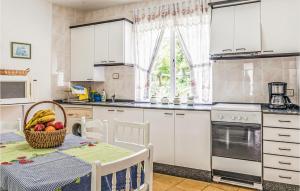een keuken met witte kasten en een tafel met een fruitmand bij Beautiful Apartment In Muros With Kitchen in Muros