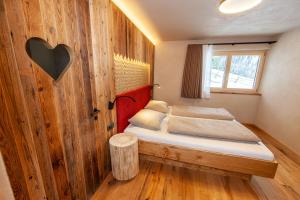 ein Schlafzimmer mit einem Bett mit einer Holzwand in der Unterkunft Biohof Oberwerkstatt in Obereggen