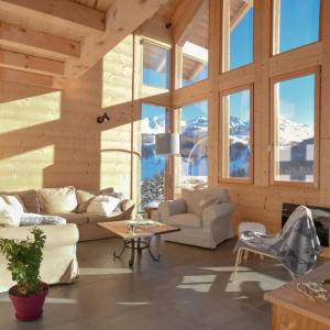 a living room with couches and a table and windows at Chalet Loan in Montgenèvre