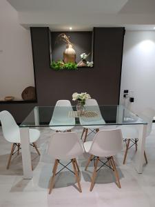 a dining room with a glass table and white chairs at LuxHoliday Apartment in Carpignano Salentino