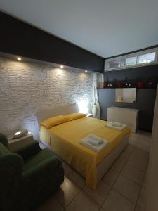 a bedroom with a yellow bed and a brick wall at LuxHoliday Apartment in Carpignano Salentino