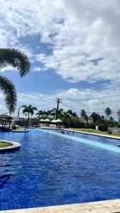 una gran piscina con agua azul y palmeras en Muro Alto Condomínio Clube Apto 219, en Ipojuca