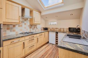 a kitchen with wooden cabinets and a skylight at Host & Stay - Church View Cottage in Matlock