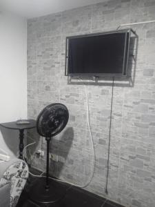 TV de pantalla plana en una pared de ladrillo con ventilador en Apartamento acogedor con Piscina Excelente Sector, en Ibagué