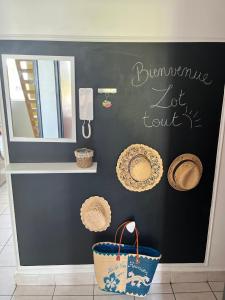 a black wall with straw hats and a mirror at Appart' Bleu Soleil in Filaos