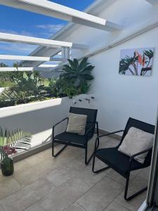 two chairs sitting on a balcony with plants at Appart' Bleu Soleil in Filaos