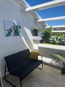 un banco negro sentado en un balcón con plantas en Appart' Bleu Soleil, en Filaos