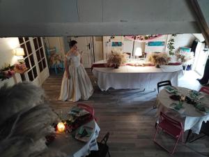 una mujer con un vestido blanco parada en una habitación con mesas en Hôtellerie Jardiniers Gourmands en Morsains