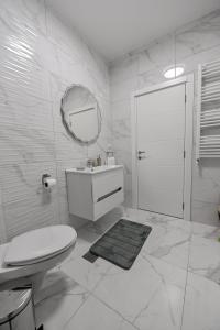 ein weißes Bad mit einem WC und einem Spiegel in der Unterkunft Porto lux in Aranđelovac