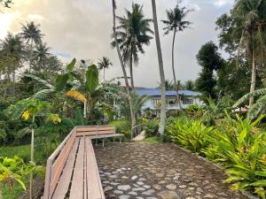 un banc en bois devant une maison plantée de palmiers dans l'établissement Agoho Resort, à Mambajao