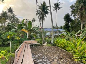 un banco de madera frente a una casa con palmeras en Agoho Resort en Mambajao