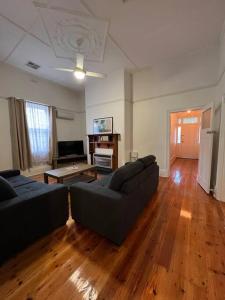 a living room with two couches and a wooden floor at Close to CBD Renovated Cottage in Prospect