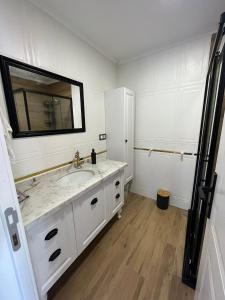 uma casa de banho branca com um lavatório e um espelho em Bahçeli villa dairesi em Trabzon