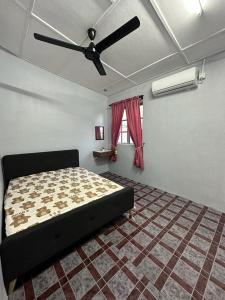 een slaapkamer met een bed en een plafondventilator bij Warisan Homestay A in Mersing