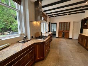 uma grande cozinha com armários de madeira e uma grande janela em Edwardian Manor near Glasgow City with HEATED POOL & HOT TUB em Giffnock