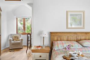 um quarto com uma cama e uma cadeira em Middle Cottage - Tranquil cottage ideal for walkers em Cornworthy