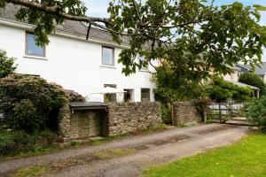 uma casa branca com uma parede de pedra e uma entrada em Middle Cottage - Tranquil cottage ideal for walkers em Cornworthy