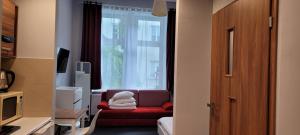 a living room with a red chair and a window at TLC Apartments Cracow in Kraków