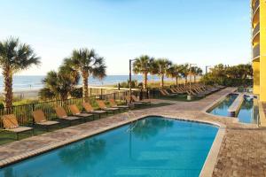 einen Pool mit Stühlen und Strand in der Unterkunft Hilton Grand Vacations Club Anderson Ocean Myrtle Beach in Myrtle Beach