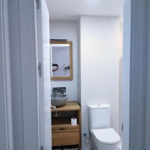 a bathroom with a white toilet and a sink at Apartamento Luz in Chiclana de la Frontera +3 photos