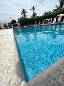 a large blue swimming pool with chairs and palm trees at هوانا صلاله in Ma‘mūrah