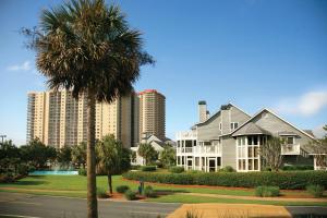 a house with a palm tree in front of tall buildings at Kingston Plantation Condos in Myrtle Beach