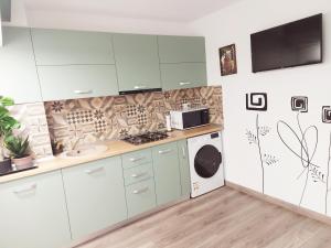 a kitchen with white cabinets and a washer and dryer at Cuza 21 in Brăila