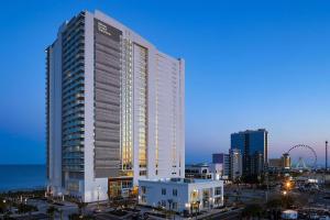 Hilton Grand Vacations Club Ocean Enclave Myrtle Beach في ميرتل بيتش: مبنى أبيض طويل في مدينة في الليل