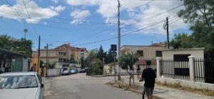 a man walking down a street with a white car at Studenti Studio's in Tirana