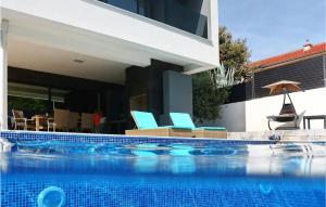 a swimming pool with two blue chairs and a house at Villa Mara in Zaton