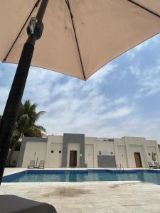 an umbrella in front of a building with a pool at هوانا صلاله in Ma‘mūrah