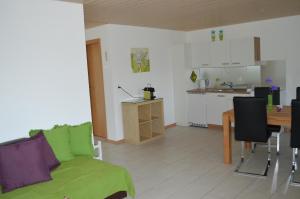 a living room with a green couch and a kitchen at Ferienhaus Stockli in Brunnen