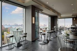 un restaurante con mesas, sillas y ventanas grandes en Hampton Inn Brooklyn Downtown en Brooklyn