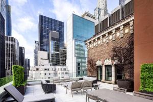 a rooftop patio with chairs and tables in a city at Hilton Club The Quin New York in New York