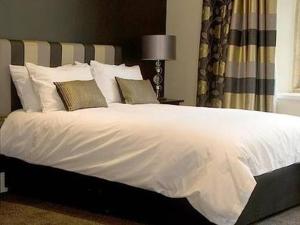 una camera da letto con un grande letto bianco con cuscini di The Keep Boutique Hotel a Yeovil