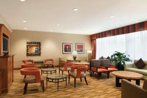 una sala d'attesa con tavoli e sedie arancioni di Hampton Inn New York - LaGuardia Airport a Queens