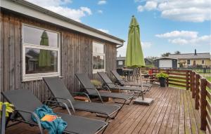 a deck with chairs and an umbrella on a building at Stunning Home In Haderslev With 4 Bedrooms And Wifi in Diernæs