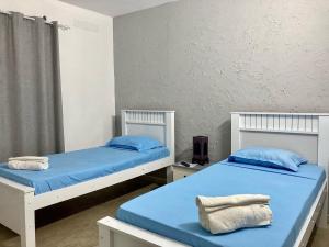 two beds in a room with blue sheets and blue pillows at Cantinho C - Alojamento Complementar in Praia