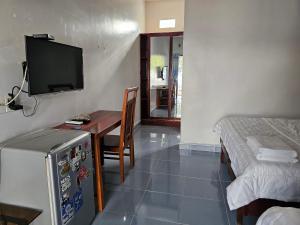 a room with a table and a bed and a television at Cay Phuong Guesthouse in Mui Ne