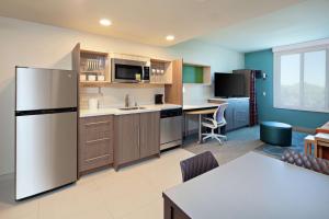 a kitchen with a refrigerator and a table in a room at Home2 Suites By Hilton Alameda Oakland Airport in Alameda