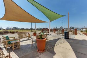 un patio con mesas, sillas y una sombrilla grande en Hampton Inn and Suites Swansboro Near Camp Lejeune, en Swansboro