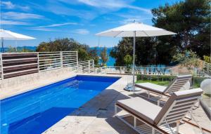 a swimming pool with two chairs and an umbrella at Villa Olea in Petrcane