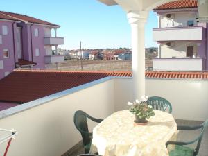a table on a balcony with a vase of flowers at Apartments Buzleta in Fažana
