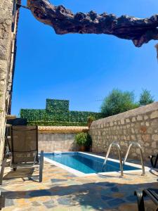 a swimming pool with a chair next to a stone wall at Windy Inns ( Maistros I ) in Vouyiáton