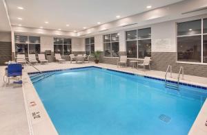 a large pool in a hotel with chairs and tables at Hampton Inn Vincennes in Vincennes