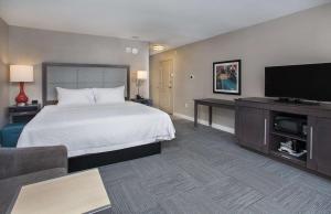 a hotel room with a bed and a flat screen tv at Hampton Inn Vincennes in Vincennes