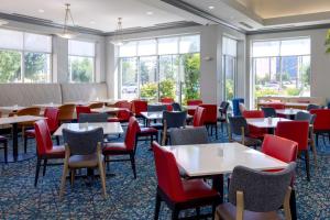 uma sala de jantar com mesas, cadeiras e janelas em Hilton Garden Inn Oklahoma City Airport em Oklahoma City