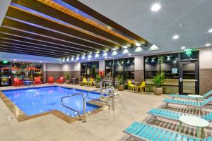 a pool in a hotel with blue chairs and tables at Home2 Suites by Hilton OKC Midwest City Tinker AFB in Midwest City
