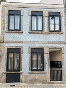 um edifício azul com quatro janelas e uma porta em Coruja’s House AL OPO no Porto